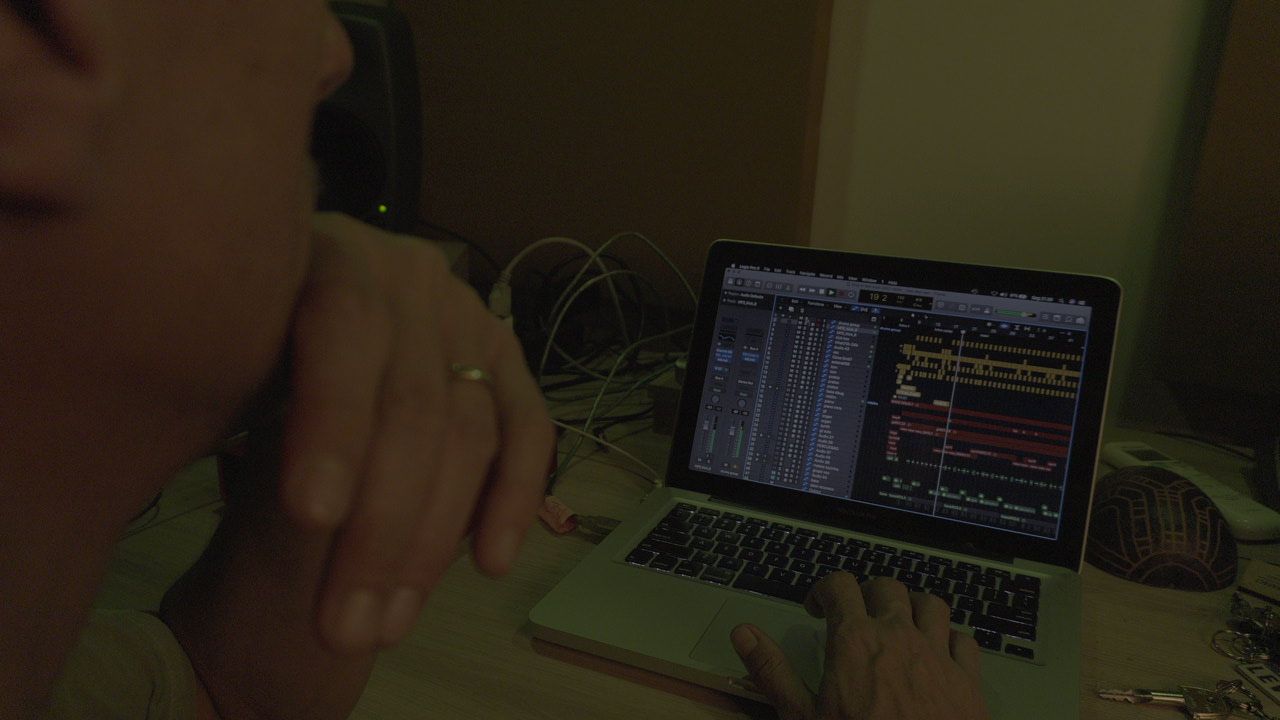 Close das mãos trabalhando em um laptop com sessão de DAW dentro do estúdio